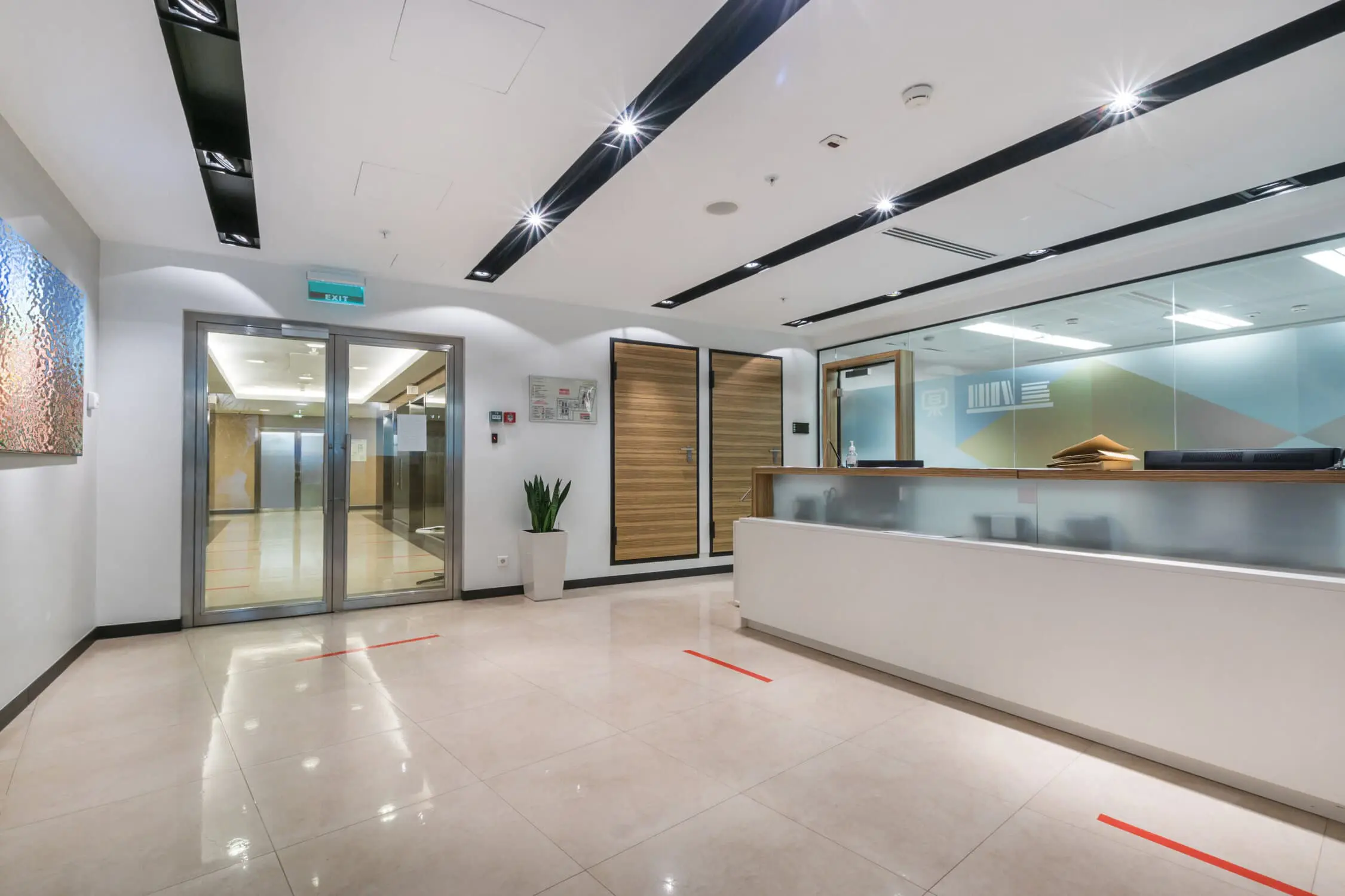 A spacious, bright office hall with a reception desk, glass door A spacious, bright office hall with a reception desk, glass doors and a picture on the wall.