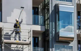 Professional painter on scaffolding painting the exterior of a commercial building in Riverview FL